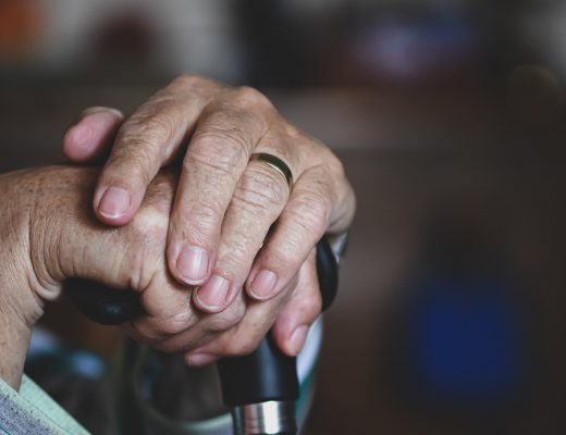 Elderly Person's Hands Holding Onto a Cane