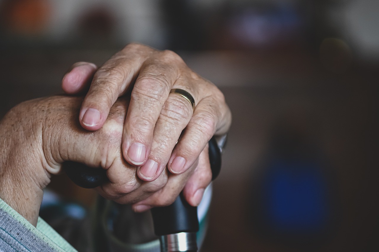 Elderly Person's Hands Holding Onto a Cane