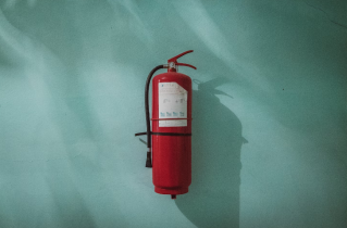 Red Fire Extinguisher Up Against a Teal Background