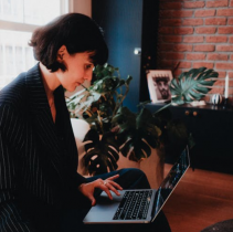 Woman Wearing a Black Blazer and Typing on a Silver Laptop