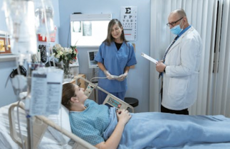 Patient in a Hospital Bed Surrounded by a Female Nurse and Male Doctor