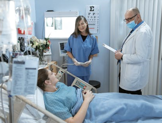 Patient in a Hospital Bed Surrounded by a Female Nurse and Male Doctor