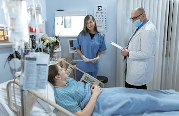 Patient in a Hospital Bed Surrounded by a Female Nurse and Male Doctor