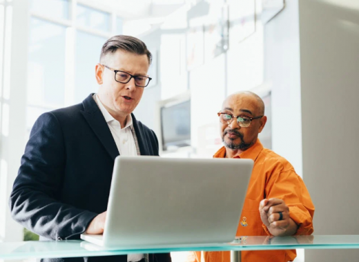 2 Men Standing and Looking at a Laptop