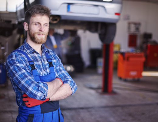 Caucasian Man Standing with Folded Arms in an Auto Repair Shop
