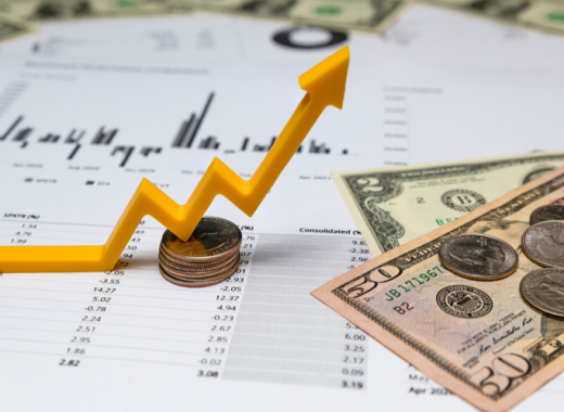 Financial Charts with Coins and Dollar Bills Sitting on Top
