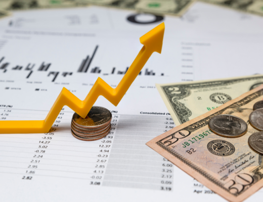 Financial Charts with Coins and Dollar Bills Sitting on Top