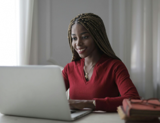 Smiling African American Woman with Long Hair Smiling at a Laptop Screen