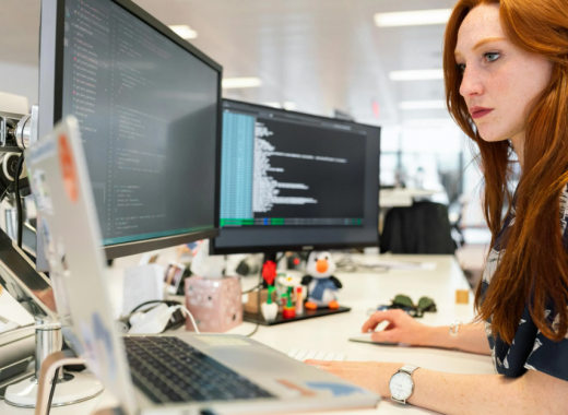 Woman with Long Red Hair Sitting in Front of Computer Monitors