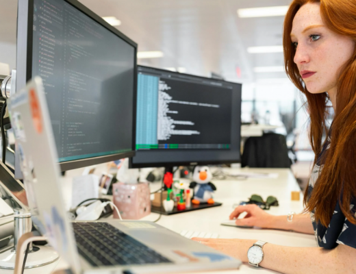 Woman with Long Red Hair Sitting in Front of Computer Monitors