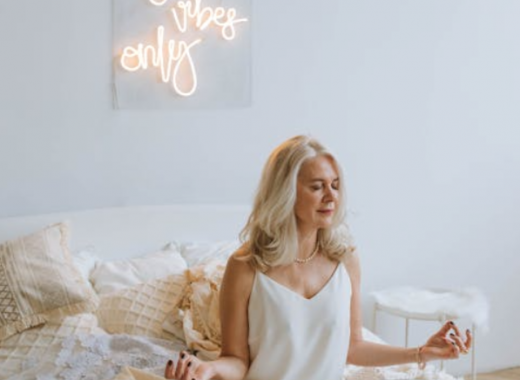 Woman Sitting on a Bed with a "Good Vibes Only" Sign Behind Her