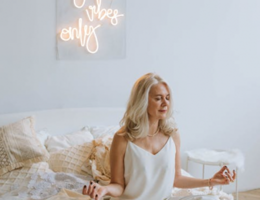 Woman Sitting on a Bed with a "Good Vibes Only" Sign Behind Her