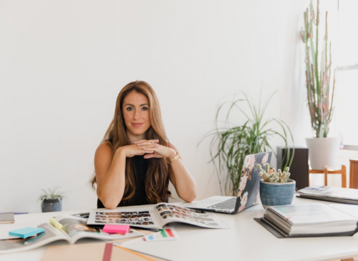 Smiling Woman Wearing a Black Dress and Sitting at a Desk