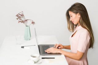 Side Profile of a Woman Wearing a Pink Dress and Typing on a Laptop