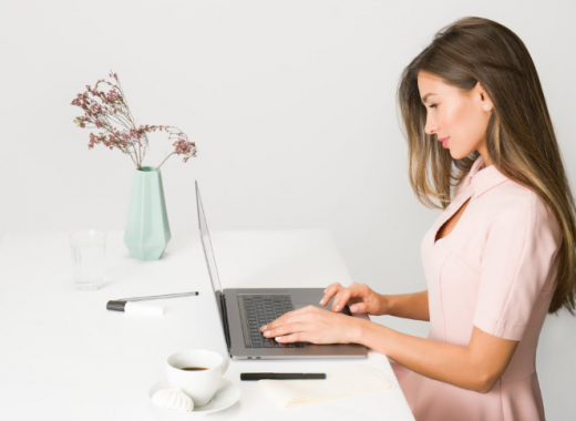 Side Profile of a Woman Wearing a Pink Dress and Typing on a Laptop