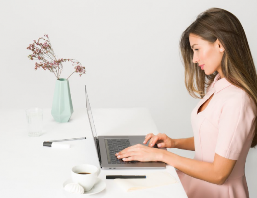 Side Profile of a Woman Wearing a Pink Dress and Typing on a Laptop