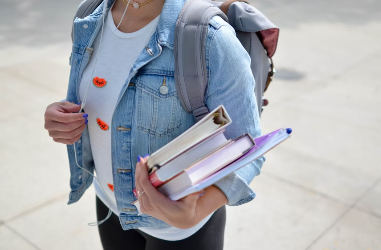 Young Student Wearing a Denim Jacket and Carrying 3 Books