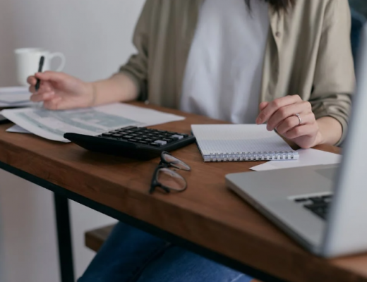 Woman Sitting at a Desk with a Laptop, Writing Tablet, and Calculator
