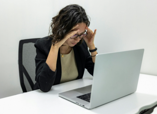 Woman Holding Her Head in Her Hands While Sitting at Her Desk