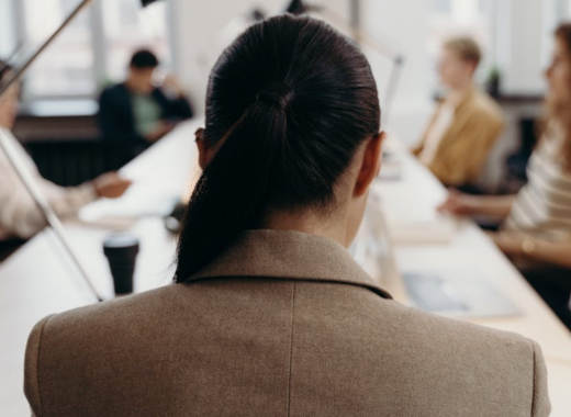 The Back of a Woman's Head Sitting at a Conference Table
