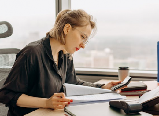 Woman Sitting at a Desk and Looking at Paperwork