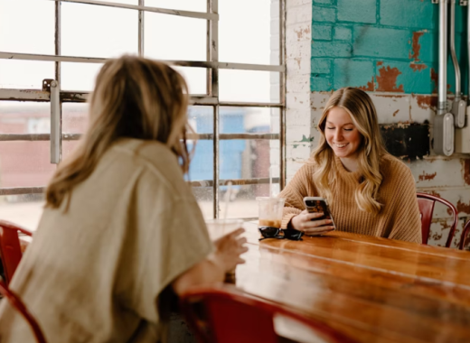 2 Smiling Women Sitting at a Rustic Conference Table