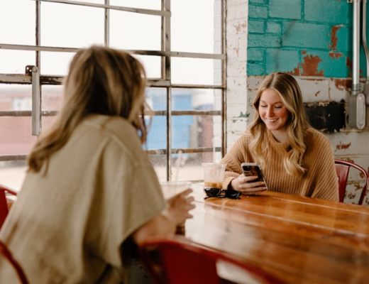2 Smiling Women Sitting at a Rustic Conference Table