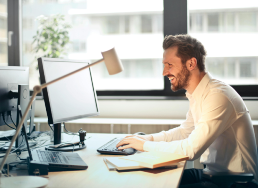 Man Smiling at a Computer Monitor