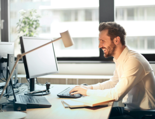Man Smiling at a Computer Monitor