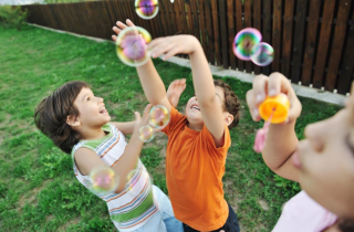 Children Playing with Bubbles in a Yard