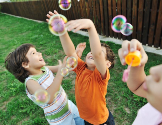 Children Playing with Bubbles in a Yard
