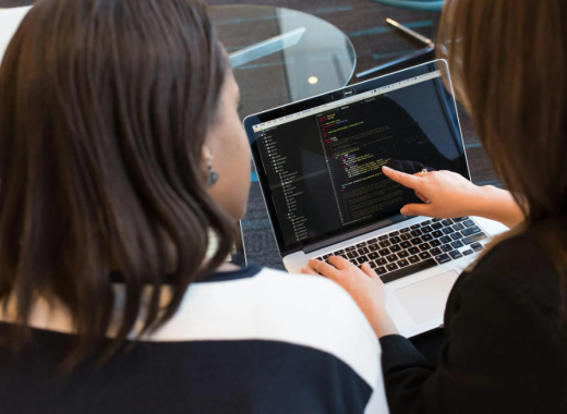 2 Women Looking at Code on a Computer Screen