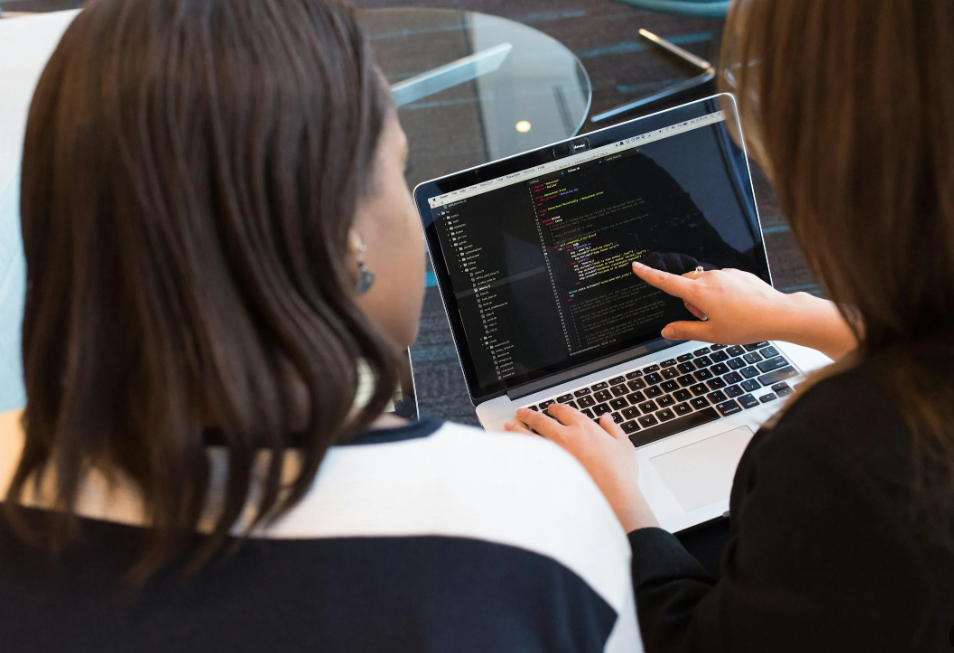 2 Women Looking at Code on a Computer Screen