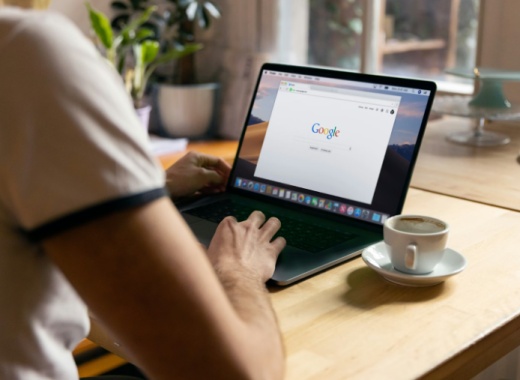 Woman Sitting at a Desk and Looking at Google Search on Her Laptop