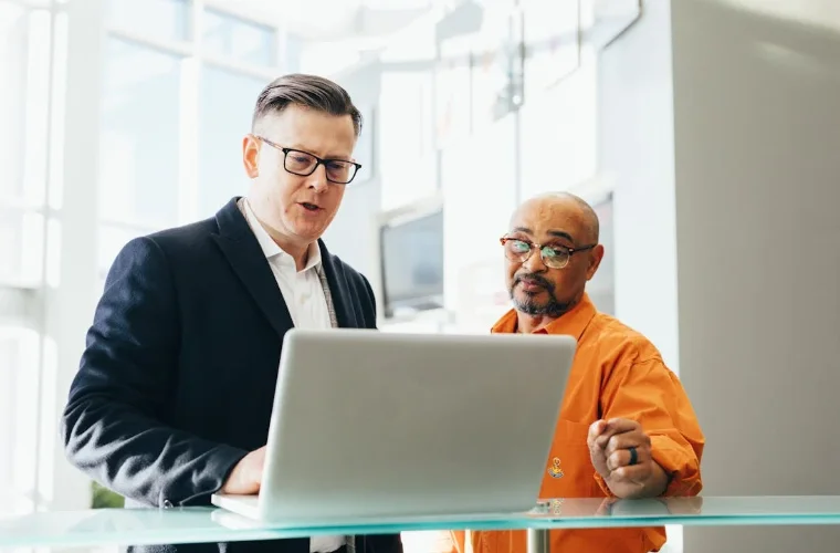 2 Men Standing and Looking at a Laptop