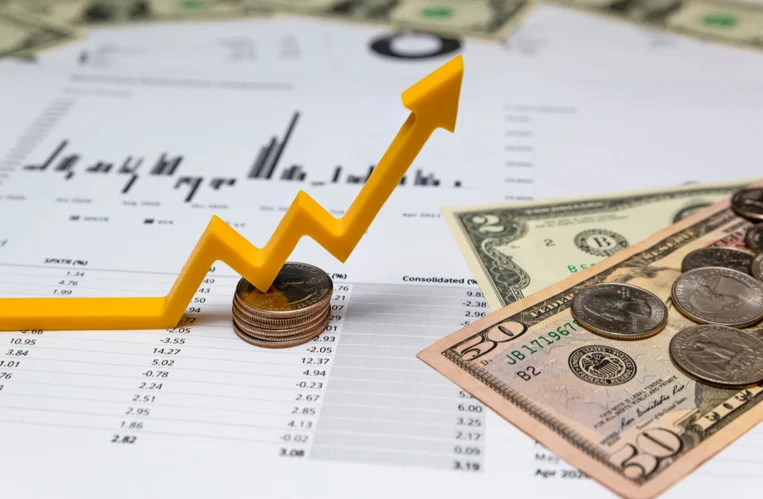 Financial Charts with Coins and Dollar Bills Sitting on Top