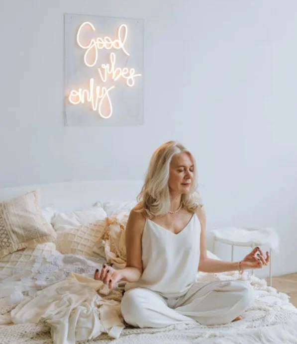 Woman Sitting on a Bed with a "Good Vibes Only" Sign Behind Her
