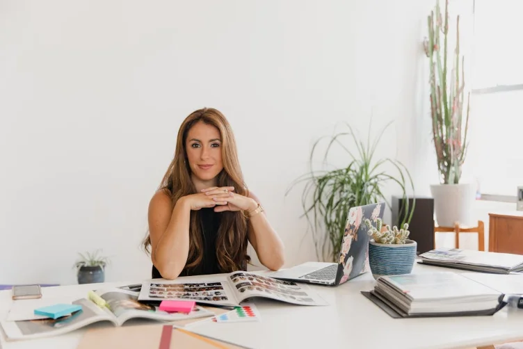 Smiling Woman Wearing a Black Dress and Sitting at a Desk