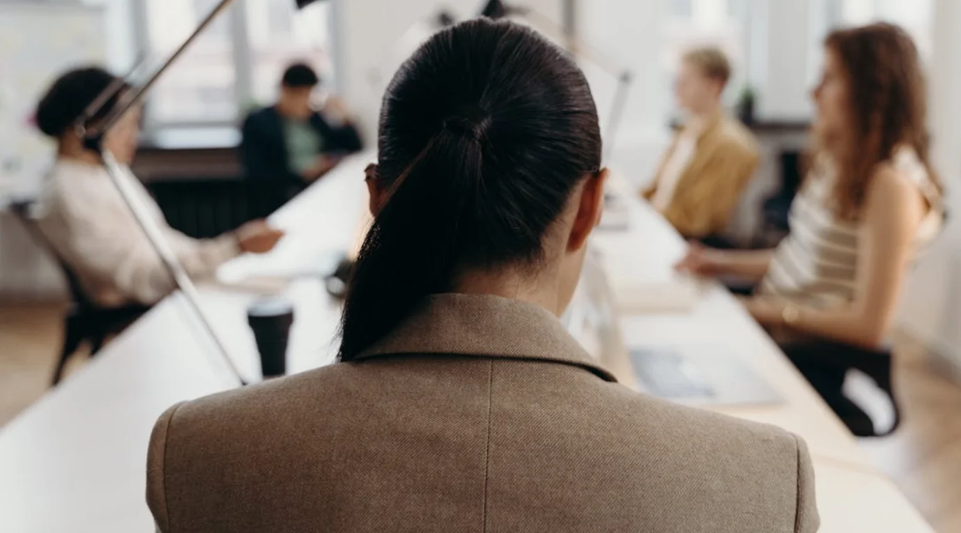 The Back of a Woman's Head Sitting at a Conference Table