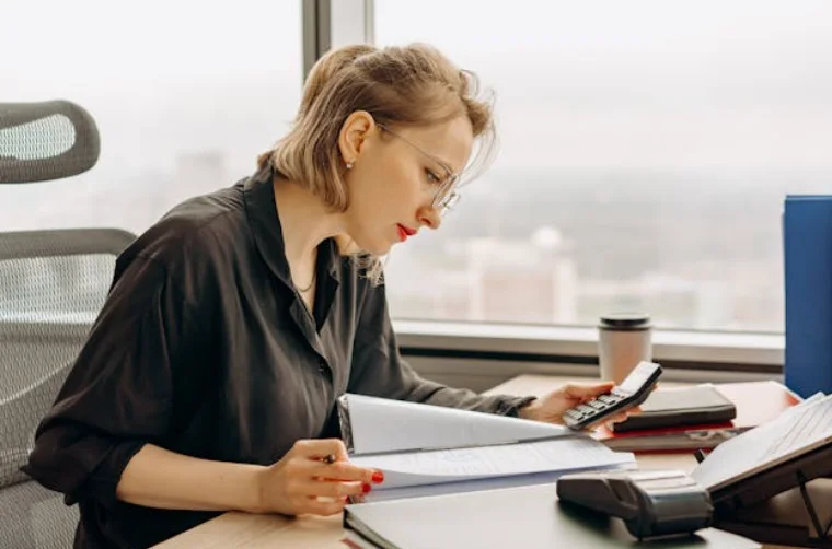 Woman Sitting at a Desk and Looking at Paperwork