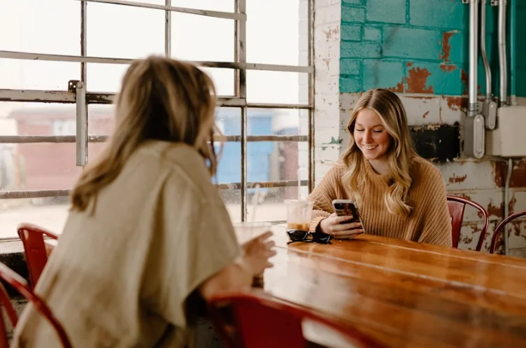 2 Smiling Women Sitting at a Rustic Conference Table