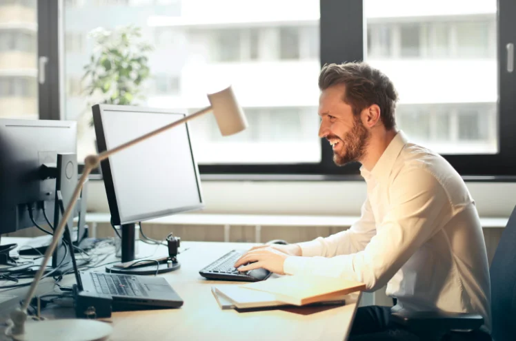 Man Smiling at a Computer Monitor